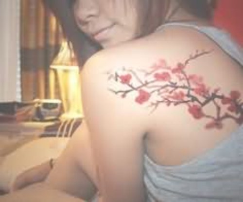 Girl Showing Her Cherry Blosoom Tattoo On Back Shoulder
